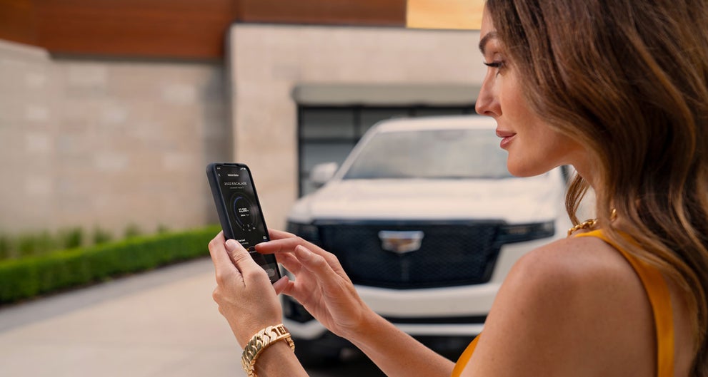 lady checking her mobile with a Cadillac vehicle background | C. Harper Cadillac in Belle Vernon PA